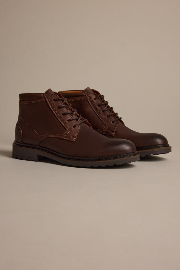 The Barkers Carlton Boot, crafted from dark brown oiled Italian leather with sturdy black soles, is displayed against a neutral beige background.