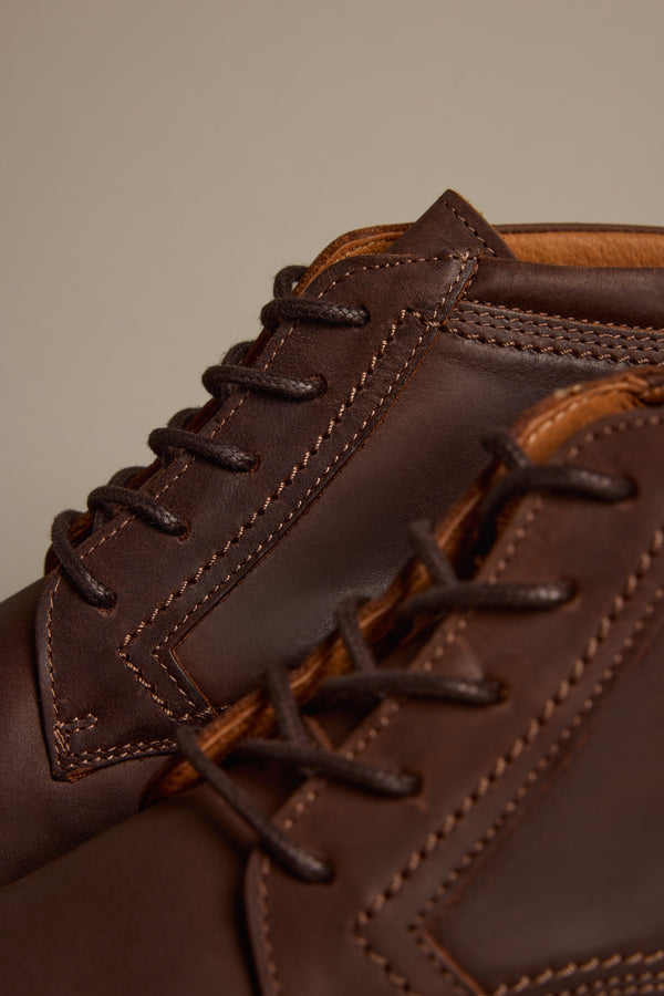 Close-up of two Barkers Carlton Boots, handcrafted with detailed stitching and brown laces from premium Italian leather, set against a neutral background.