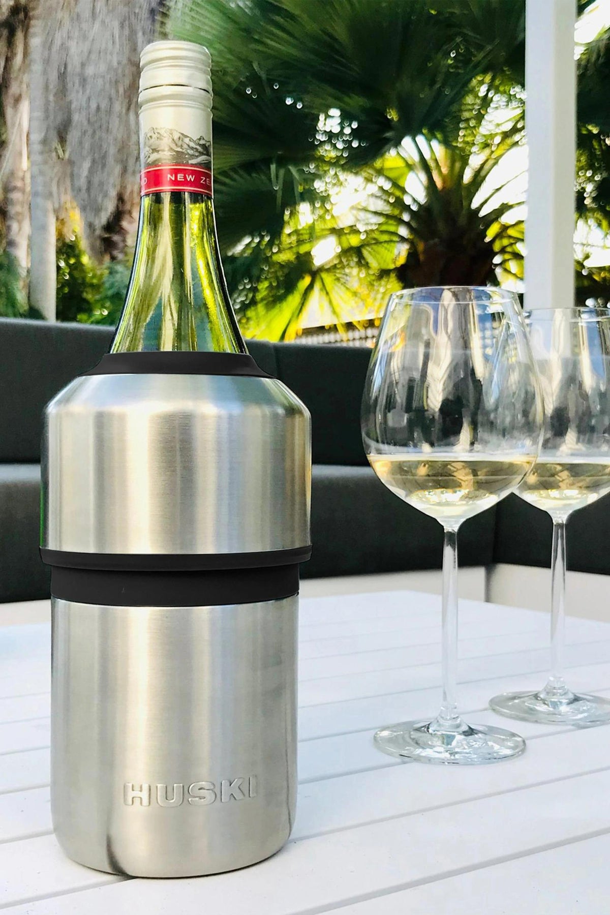 Huski Wine Cooler by Huski chilling a bottle with two glasses on an outdoor table.